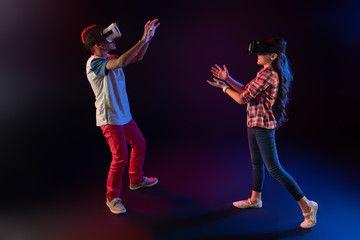Spending time together. Inspired adorable girl and a boy wearing VR headsets and playing an interesting game