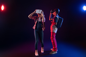 Fototapeta premium Lovely day. Smiling sweet girl and a boy wearing VR headsets and having their schoolbags on