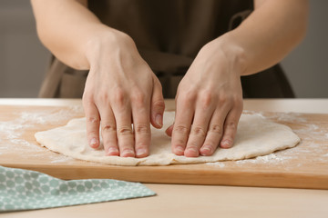 Obraz na płótnie Canvas Woman preparing dough for pizza on table in kitchen, closeup