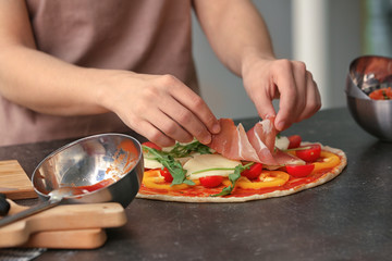 Woman preparing pizza at table in kitchen
