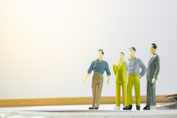 A group of miniature business man on paper with wooden table.