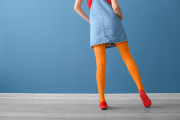 Stylish woman in bright tights against color wall