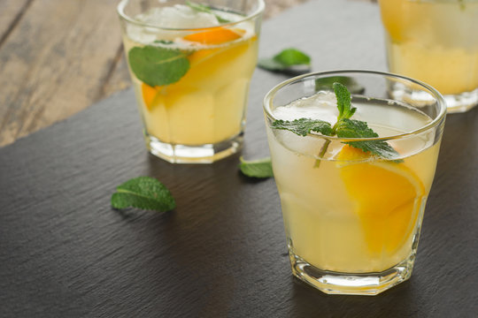 Cocktail. Orange juice with mint and ice on rustic wooden table