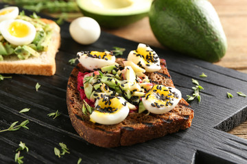 Tasty toast with avocado on wooden board