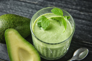 Ripe avocados and glass of tasty smoothie on wooden background
