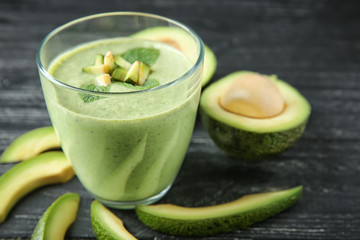 Glass of tasty avocado smoothie on wooden table