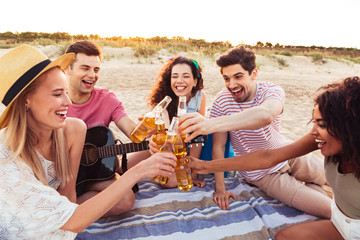 Group of young smiling friends 20s in summer clothes hanging out together, and drinking beverages at beach party