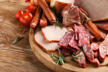 Wooden board with assortment of delicious deli meats on wooden board