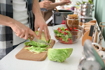 Young man with friends cooking in kitchen