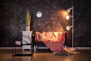 Modern interior with comfortable sofa near dark wall