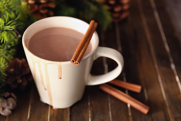 Cup of hot cocoa with cinnamon sticks on wooden table