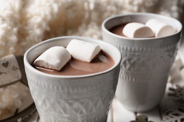 Cups of hot cocoa with marshmallows on table, closeup