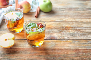 Tasty apple drink with cinnamon in glasses on wooden table