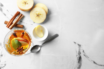 Obraz na płótnie Canvas Tasty drink with cinnamon and apple slices in glass on light table