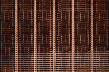 Detailed texture of engine water cooling radiator with vertical lines. Background image of orange automobile part with copy space close up.