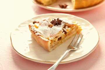 Plate with piece of delicious apple pie on light background, closeup