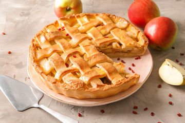 Plate with delicious apple pie on grey background