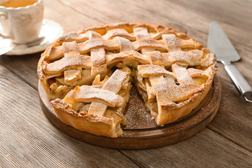 Board with delicious apple pie on wooden table