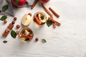 Glasses of tea with cinnamon and apples on table