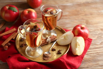 Glass cups of tea with cinnamon and apples on wooden table