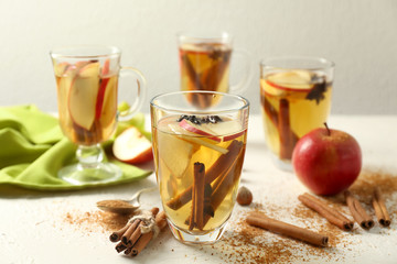 Glasses of tea with cinnamon and apples on table