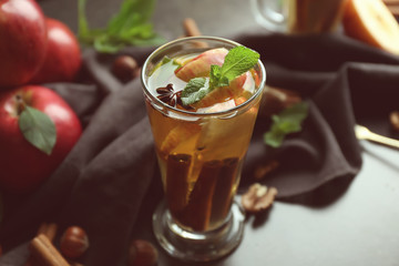 Glass cup of tea with cinnamon and apples on dark background