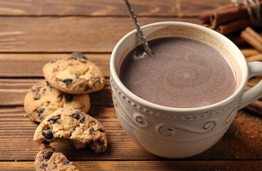 Cup of delicious hot cocoa and cookies on wooden background