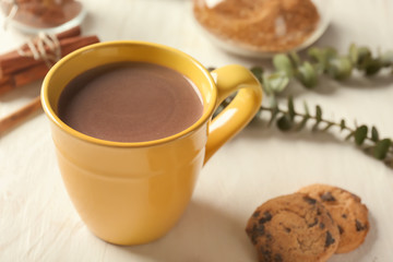 Cup of delicious hot cocoa and cookies on wooden background