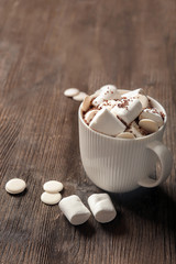 Cup of delicious hot cocoa with marshmallows on wooden background
