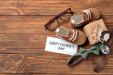 Composition with gift box, small shoes and bow tie on wooden background. Happy Father's Day