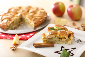 Plate with piece of delicious apple pie on table