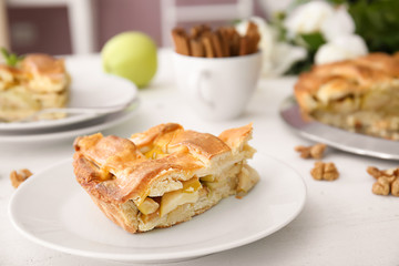 Plate with piece of delicious apple pie on wooden table