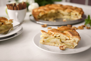 Plate with piece of delicious apple pie on wooden table