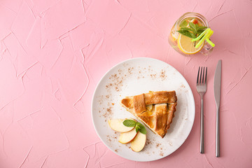 Plate with piece of delicious apple pie on color background, top view
