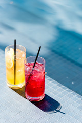close-up shot of glasses of delicious fruit cocktails on poolside