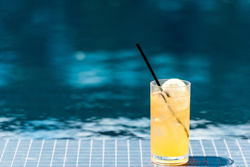 close-up shot of glass of tasty orange cocktail on poolside