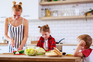 Image of beautiful woman with her daughter and son cooking food in kitchen
