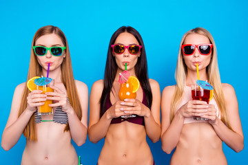 Portrait of cool trio drinking colorful cocktails from tubule looking at camera isolated on vivid...