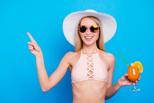 Advertisement weekend holiday recommend concept. Portrait of positive charming girl holding alcohol cocktail in hand gesturing product with forefinger isolated on vivid blue background