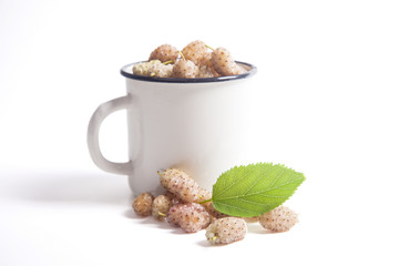 White cup with white mulberry fruit and leaf isolated on white.