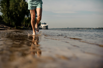 Muscular male feet running along the river bank