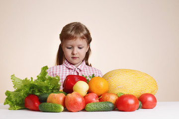 Fototapeta na wymiar little girl and a lot of fruit and vegetables. Concept of