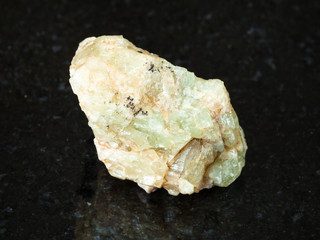 rough green beryl crystal on black granite
