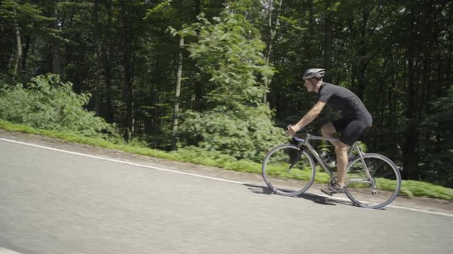 4K video man on racing bike cycling on road through forest
