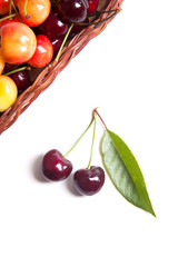 Yellow and red sweet cherry in basket with green leaf isolate on white.