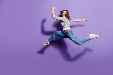 Portrait of fit sporty girl jumping over in the air looking at camera having good stretching...