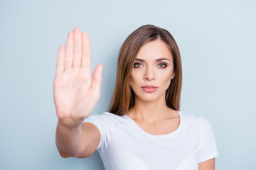 Portrait of gorgeous confident girl in white t-shirt  gesturing blurred palm front, stop sign fighting with violence isolated on grey background