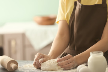 Obraz na płótnie Canvas Woman kneading dough on kitchen table