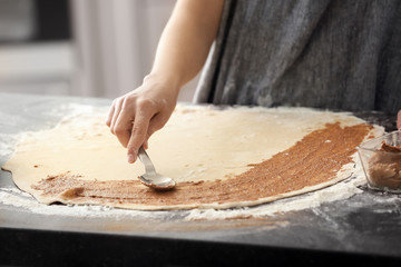 Woman making cinnamon rolls in kitchen