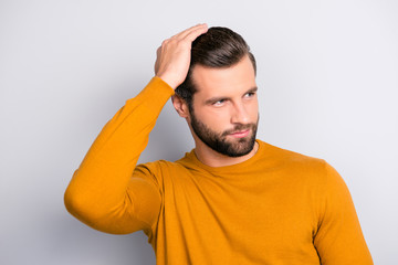 Close up portrait of attractive handsome virile masculine brutal guy combing back his long brown-haired furfur looking aside wearing color of mustard tight pullover isolated on gray background